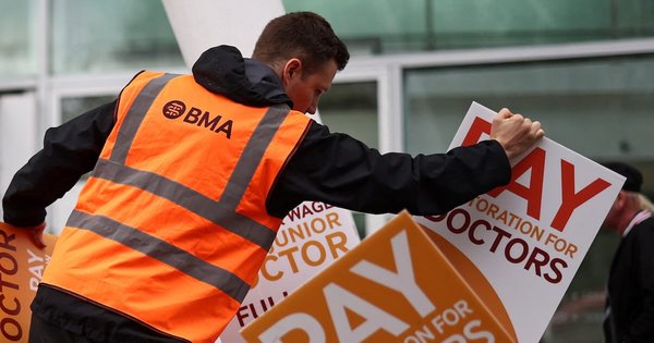 An organiser arranges BMA-branded placards calling for better pay outside a hospital in central London in 2023.